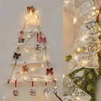 Decorative Christmas tree made of ribbons with lights and small ornaments on a plain background.