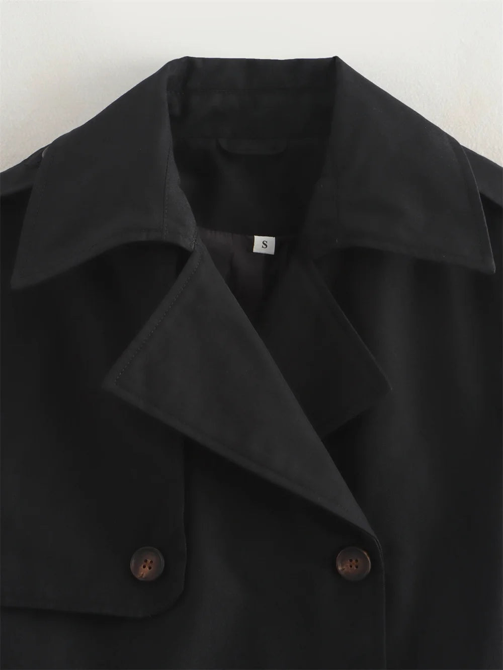 Black coat with button details on a white background