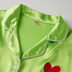 Green satin robe with red heart design and white buttons on a light gray background