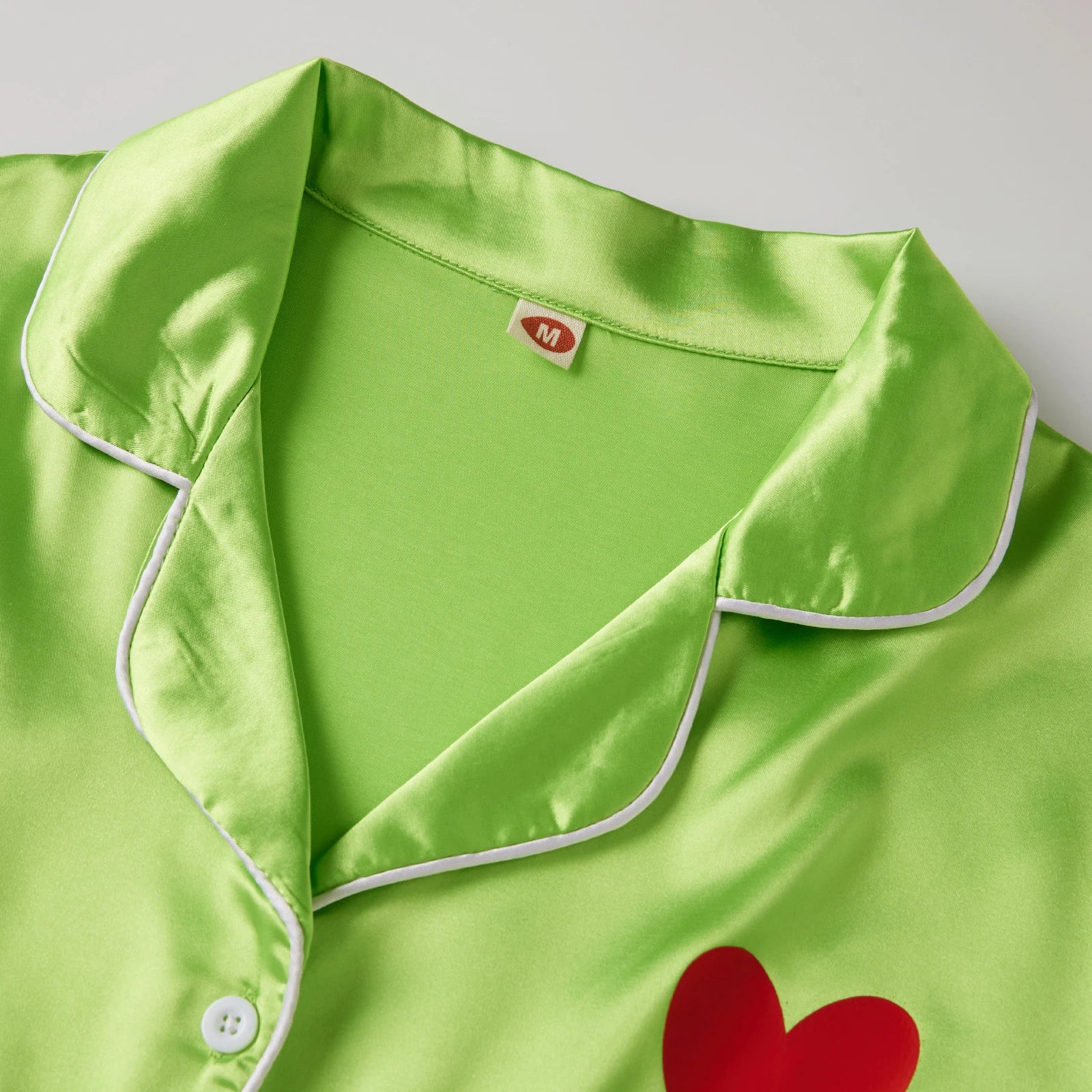 Green satin robe with red heart design and white buttons on a light gray background