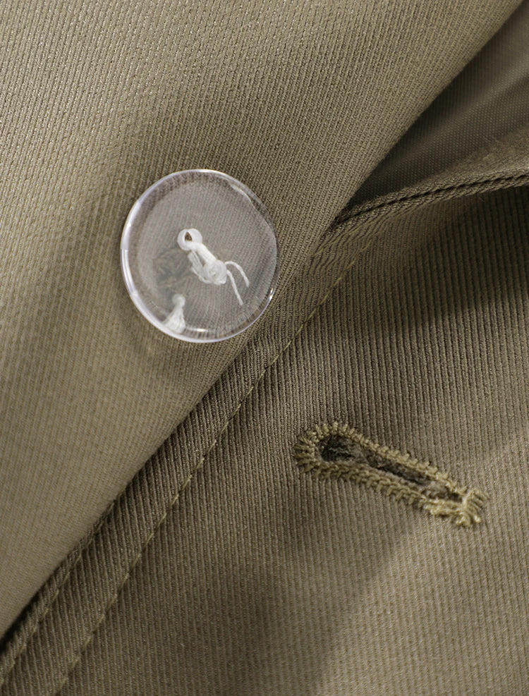 Close-up of a button on a brown fabric with a brand logo.