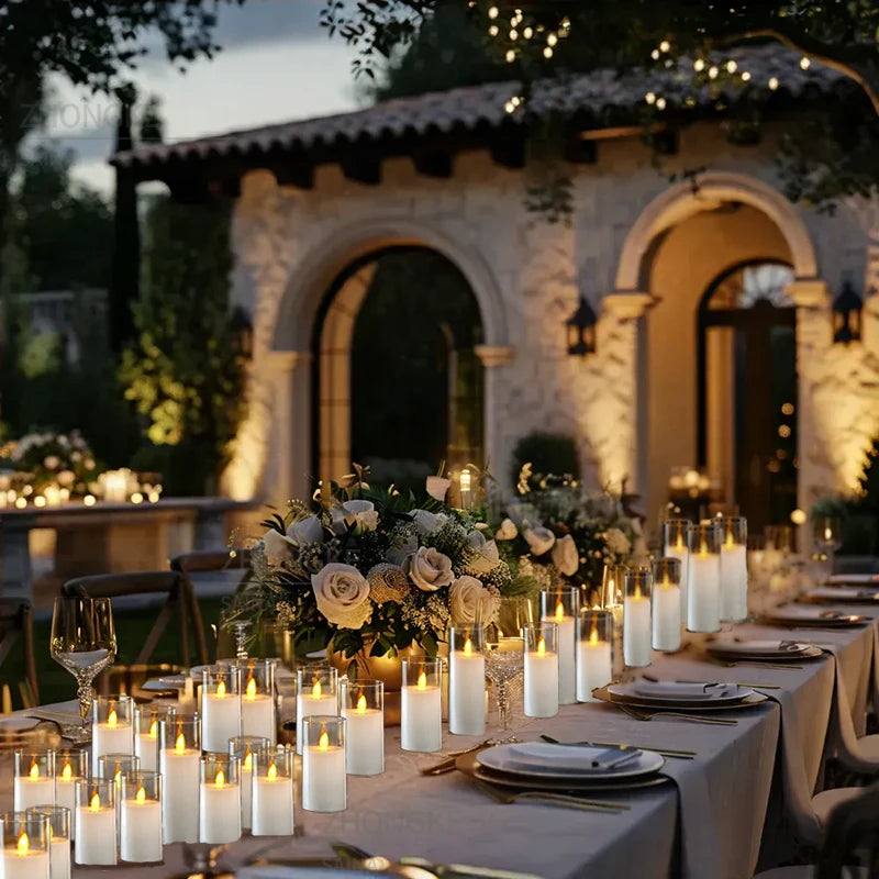Elegant outdoor dinner table setting with candles and flowers in front of a stone building.