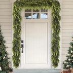 Front door with a green wreath and Christmas trees on either side