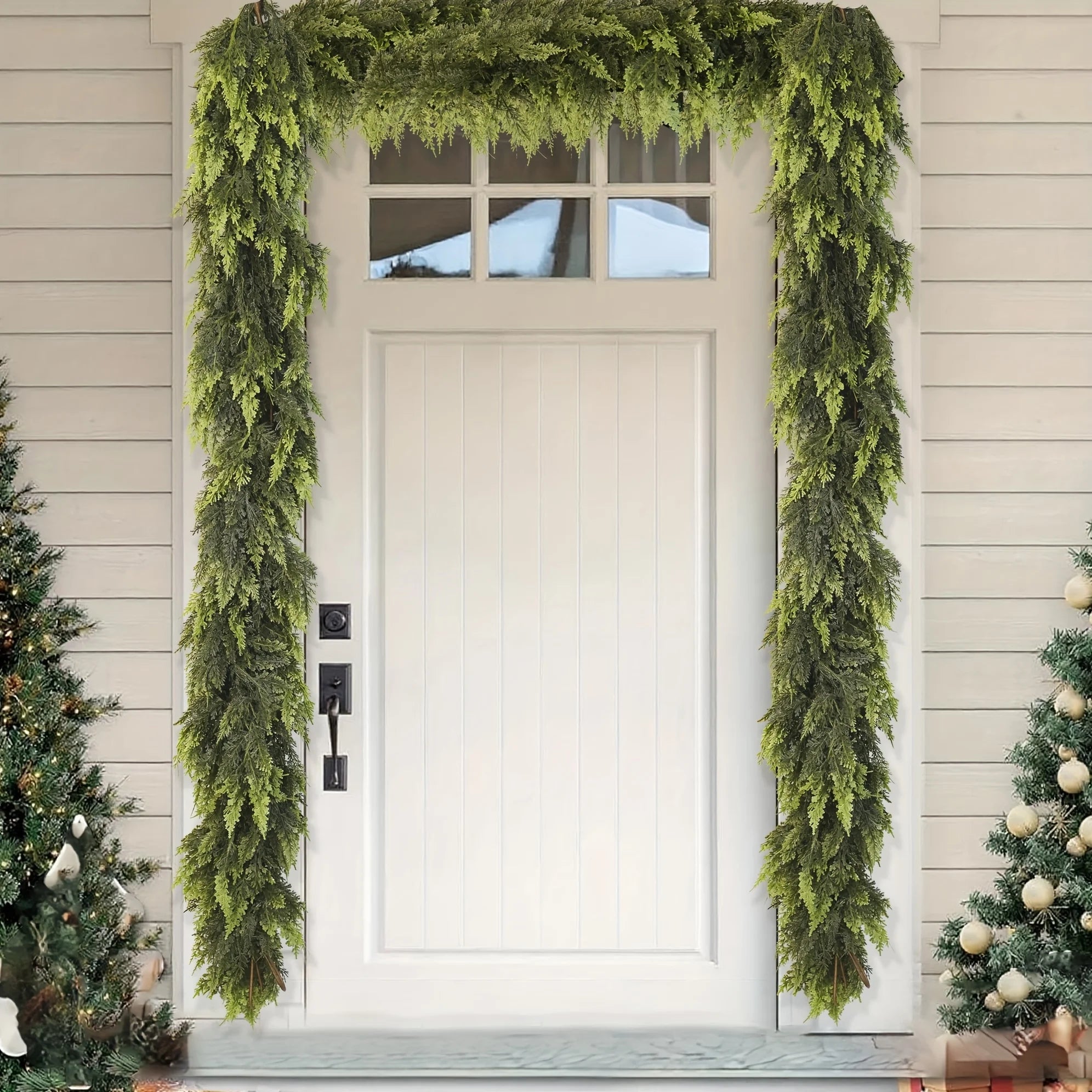 Front door with a green wreath and Christmas trees on either side