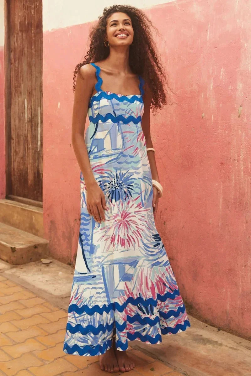 Woman wearing a colorful dress standing against a pink wall.