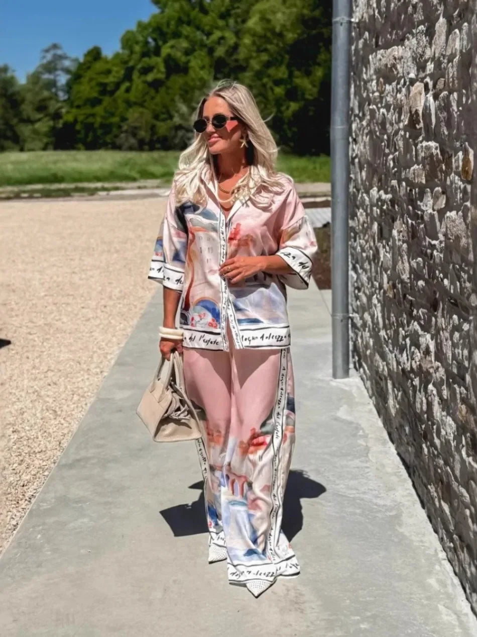 Woman in a colorful outfit walking outdoors near a stone wall.