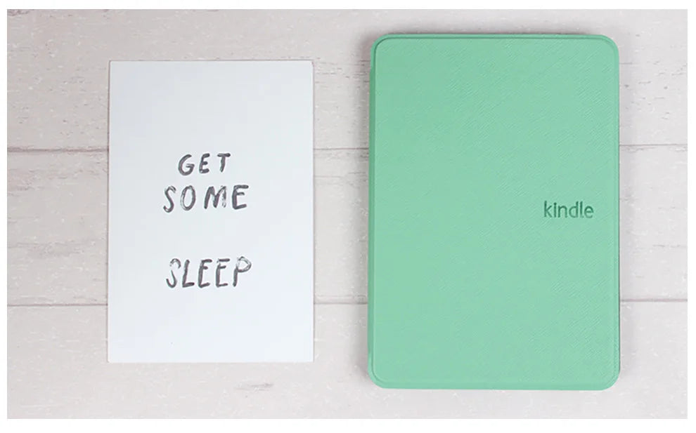 Green 'Kindle' cover on a white surface with a sign reading 'Get some sleep'.