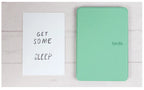 Green 'Kindle' cover on a white surface with a sign reading 'Get some sleep'.