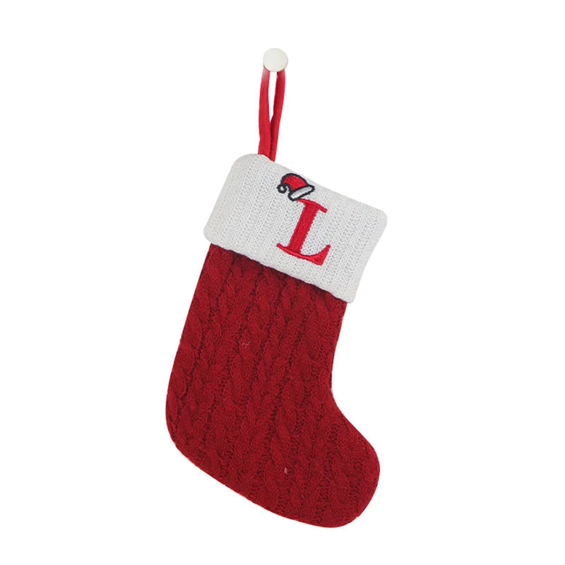 Red knitted Christmas stocking with white cuff featuring a letter 'L' on a white background