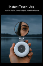 Hand holding a compact mirror with a built-in light, reflecting a person's eye against a dark background.