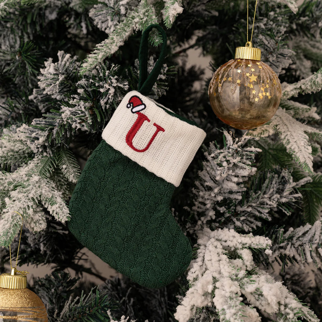 Green Christmas stocking with a red letter 'U' on a decorated tree
