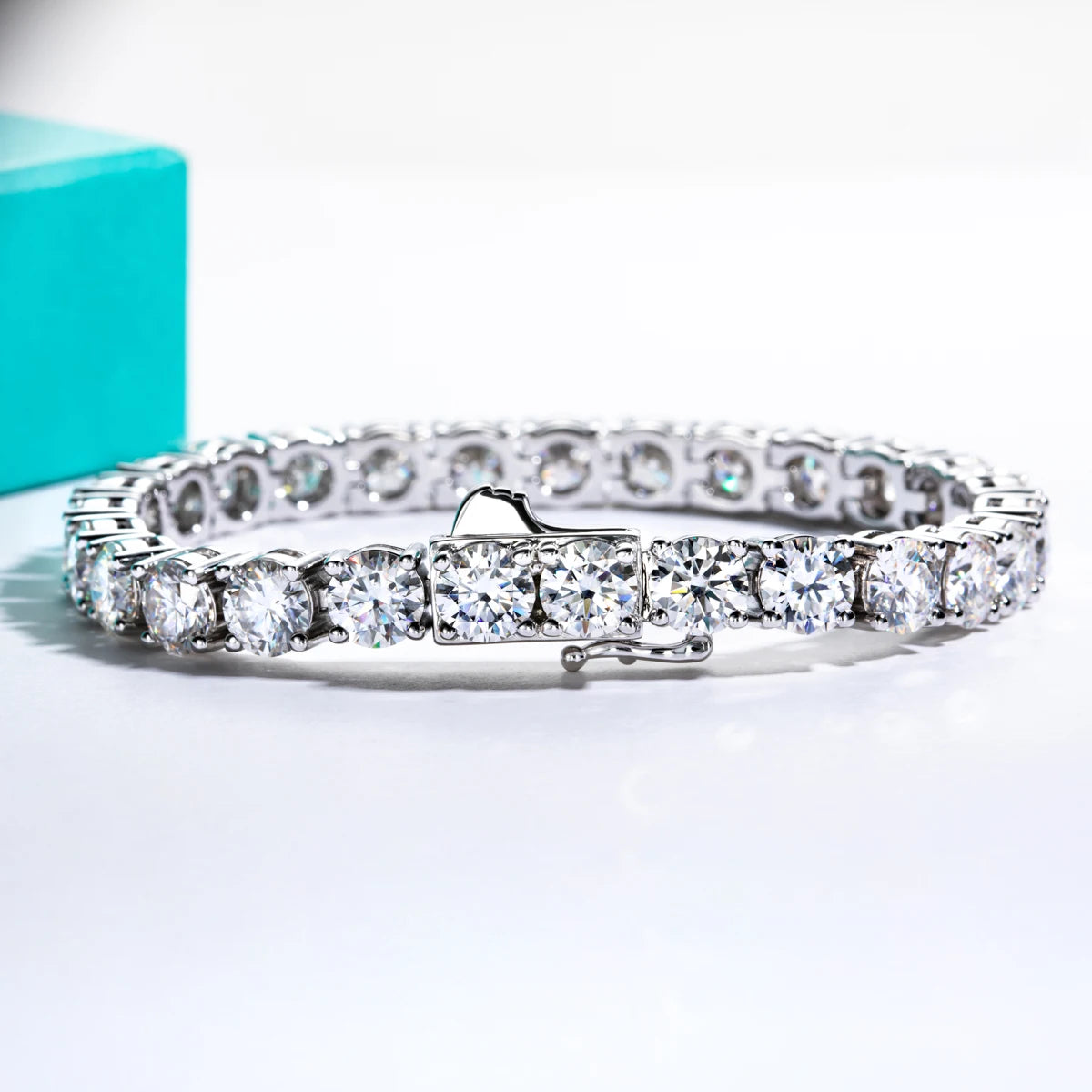 Diamond bracelet on a white surface with a teal box in the background