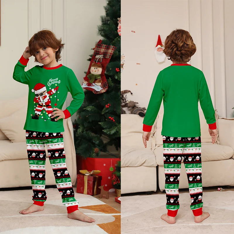 Child wearing a green Christmas-themed pajama set with a tree and presents in the background.