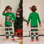 Child wearing a green Christmas-themed pajama set with a tree and presents in the background.