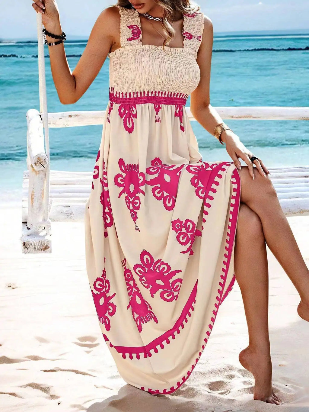 Woman in a beige and pink dress on a beach swing with ocean view
