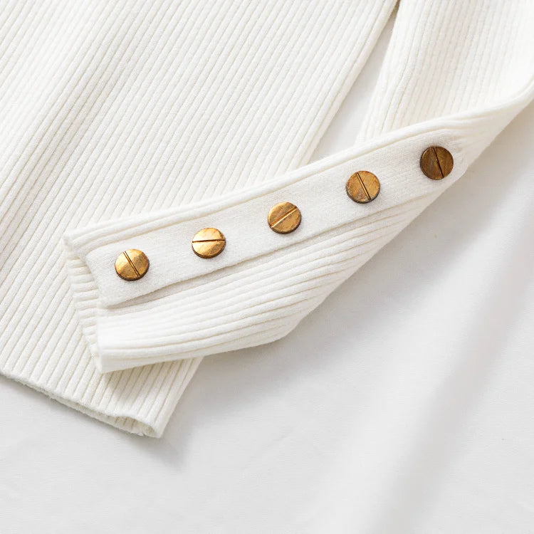 Close-up of a white ribbed sweater with gold buttons on a light background