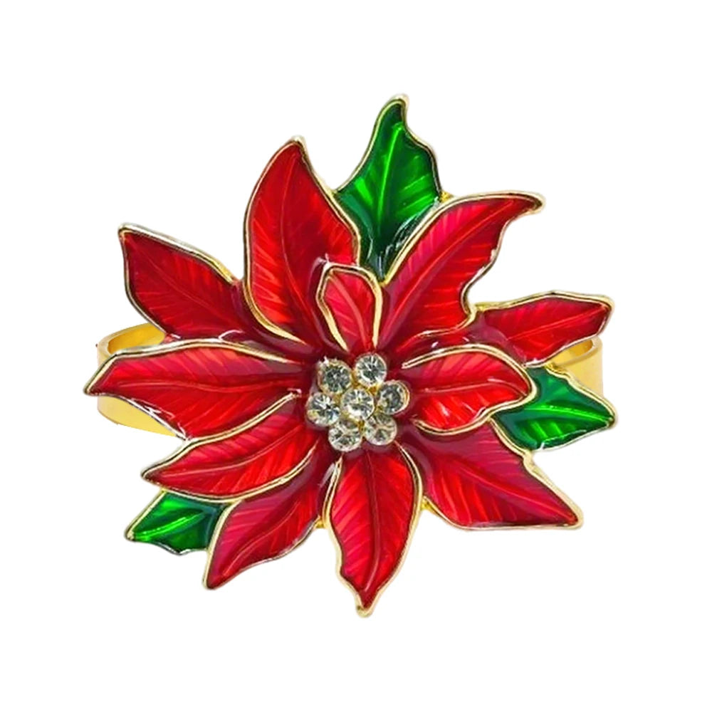 Red and green poinsettia flower brooch with a central gemstone on a white background