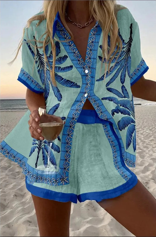 Woman in a blue and green outfit with palm tree design on a beach.