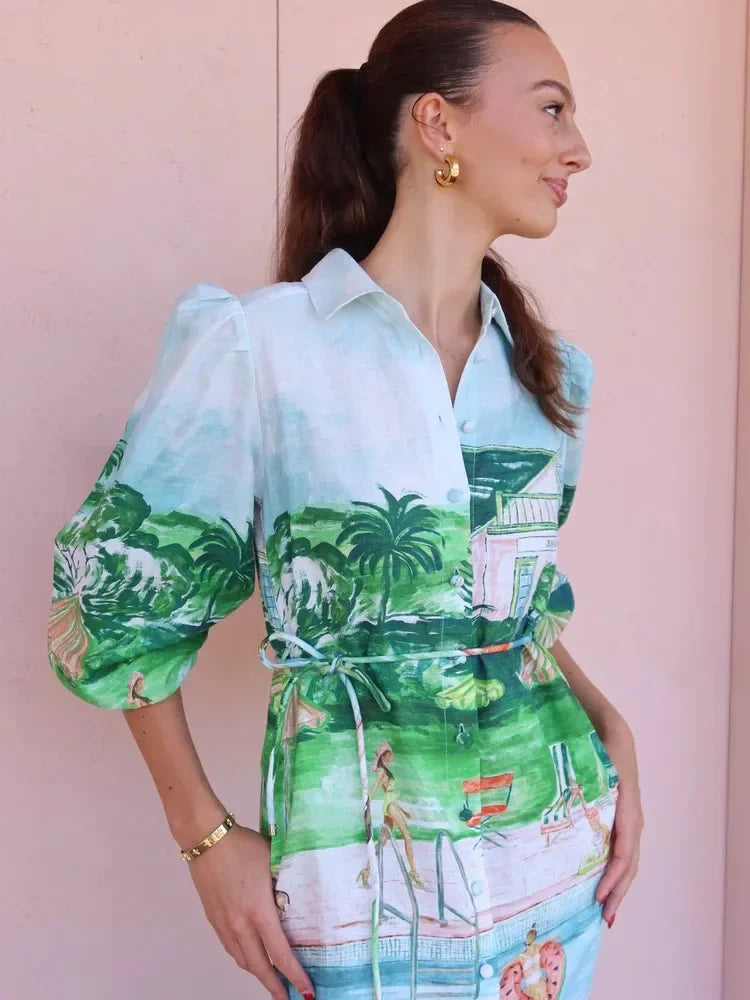 Woman wearing a colorful shirt with a palm tree design against a pink background