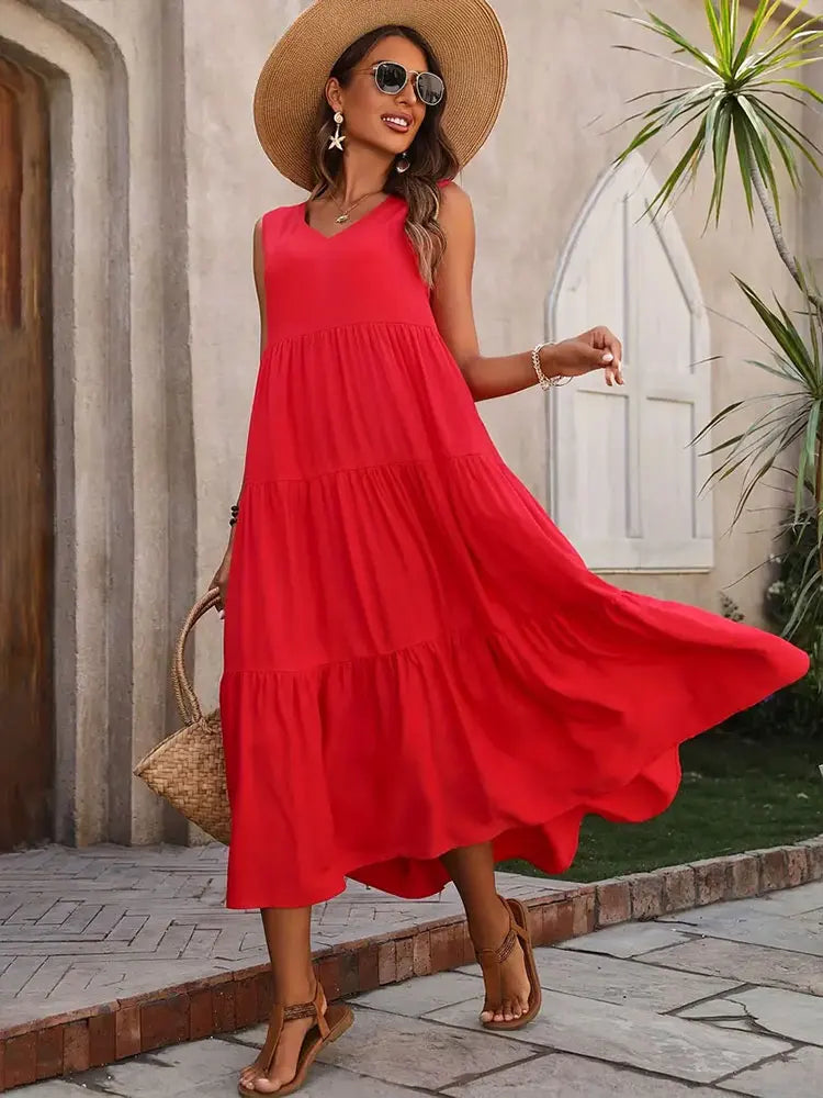 Woman in a red dress and straw hat standing outdoors.