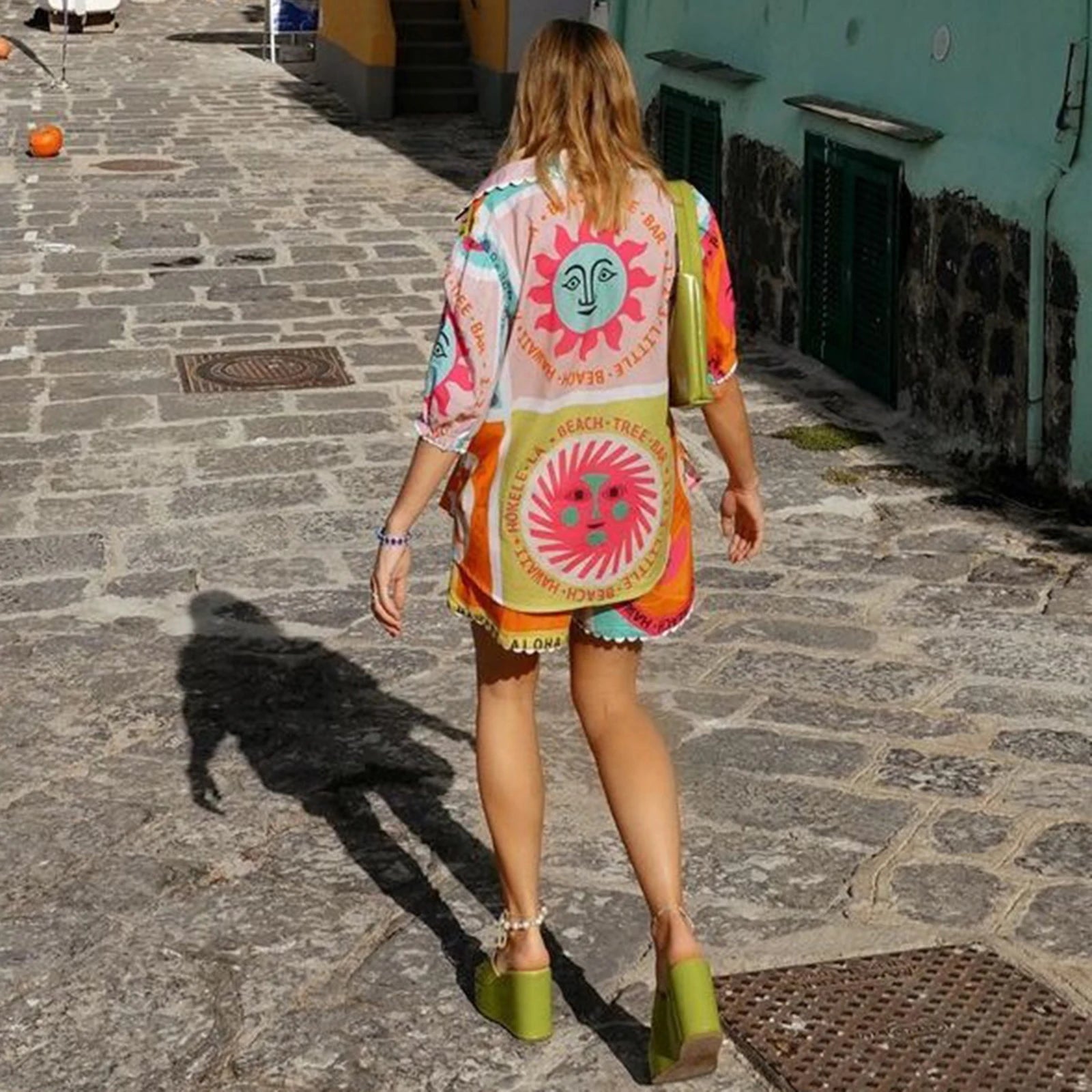 Woman wearing a colorful kimono-style garment with a sun design on a stone street.