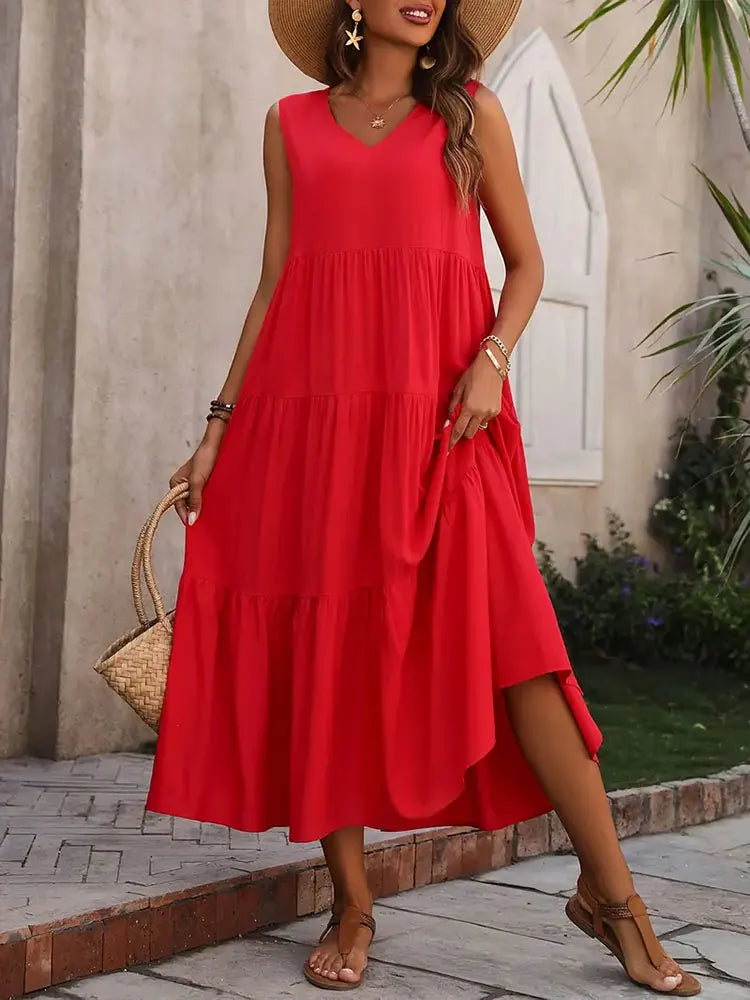 Woman wearing a red dress with a straw bag and sandals, standing outdoors.