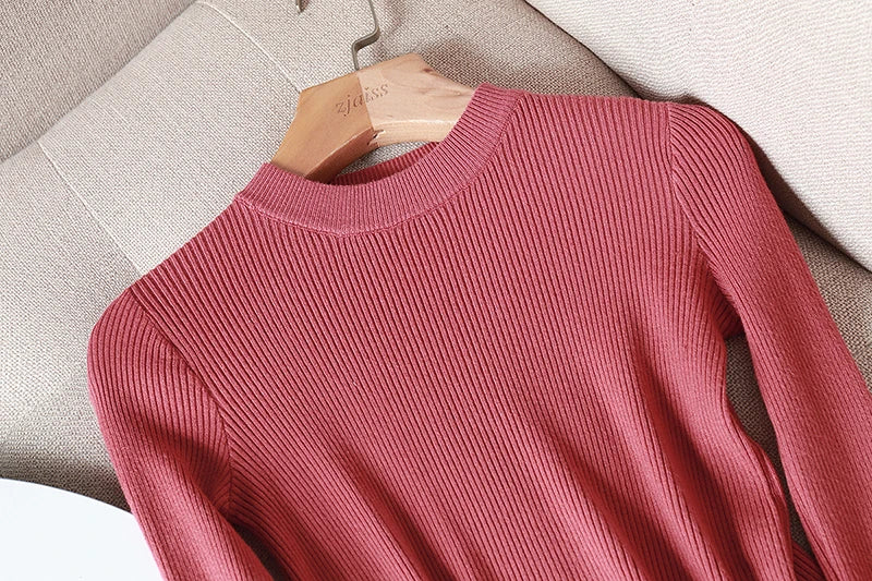 Pink sweater on a wooden hanger against a beige background