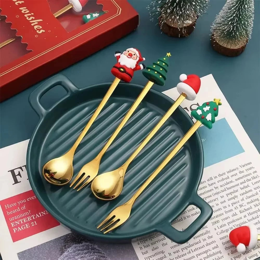 Set of gold Christmas-themed spoons on a green plate with a red gift box in the background.