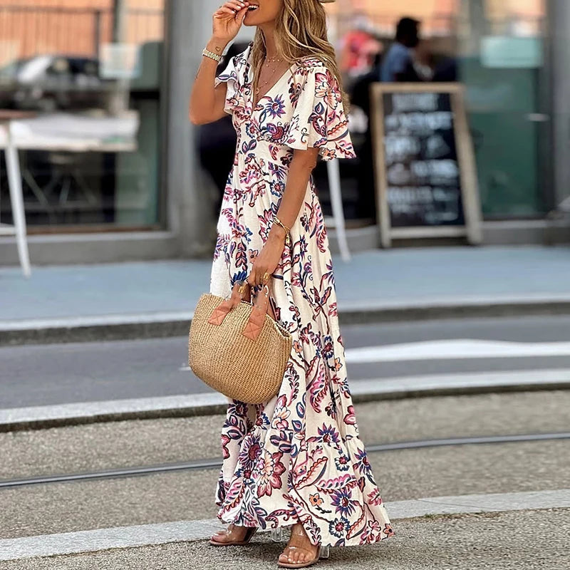 Woman in a floral dress holding a straw bag on a street.