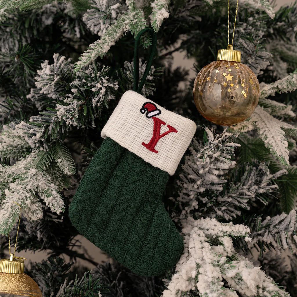 Green knitted stocking with a red 'Y' hanging on a Christmas tree.