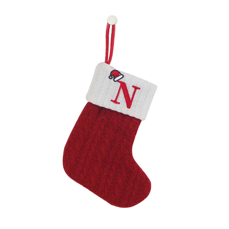 Red knitted Christmas stocking with a white cuff featuring a red 'N' and a small Santa hat, on a white background.