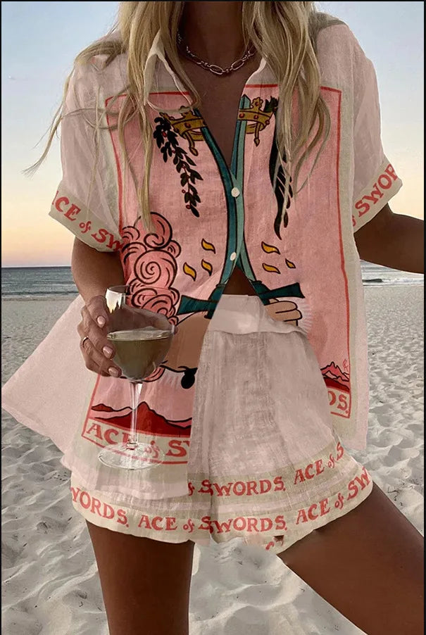Person wearing a stylish outfit with a pink and white patterned shirt and shorts on a beach.