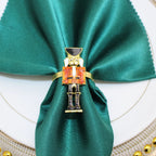 Napkin ring shaped like a nutcracker on a green napkin with a white plate background