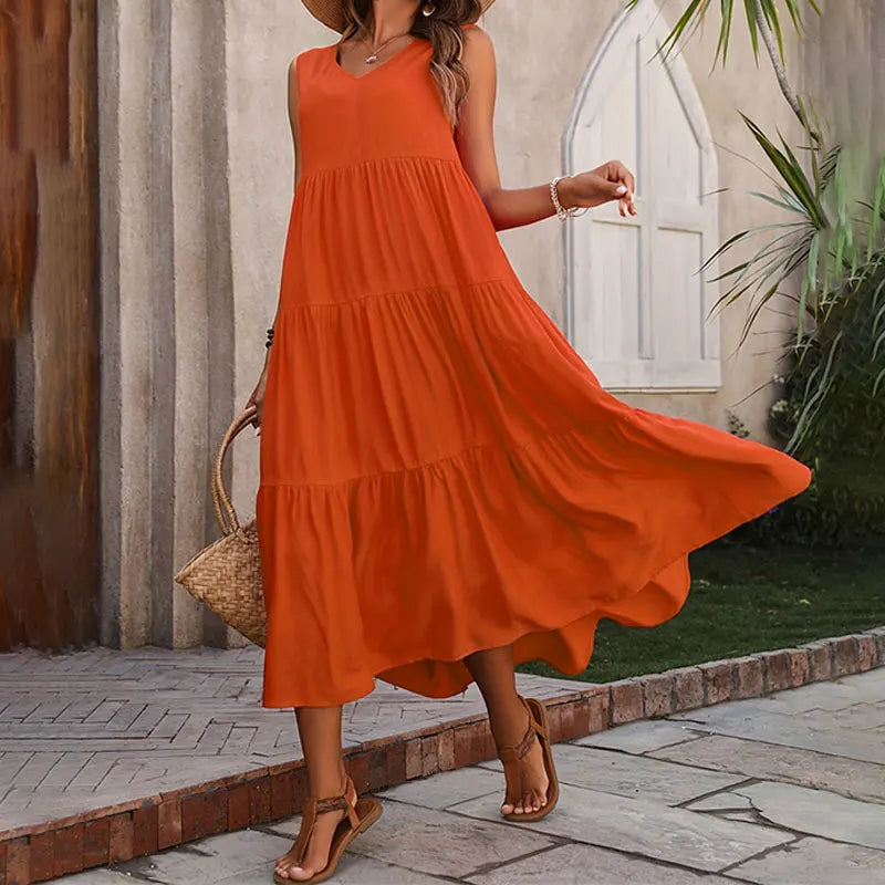 Woman wearing an orange dress standing outdoors on a stone path.