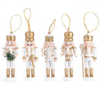 Set of five nutcracker ornaments with gold and white attire on a white background