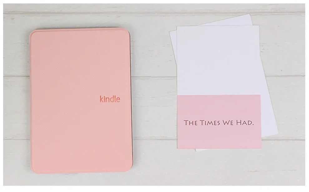 Pink 'Kindle' cover and white book with 'The Times We Had' text on a light wooden surface.