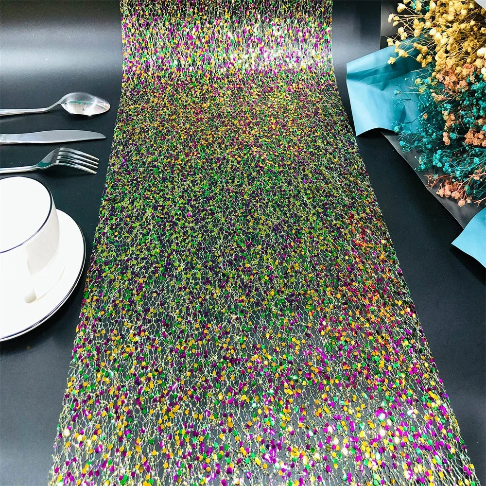 Colorful sequin table runner on a black table with silverware and a bowl.