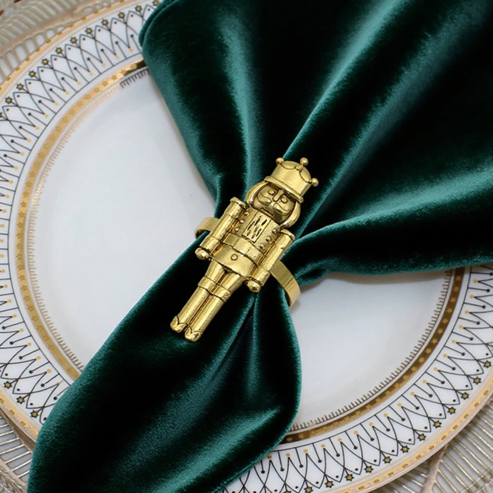 Gold nutcracker napkin ring on a green napkin with a decorative plate in the background