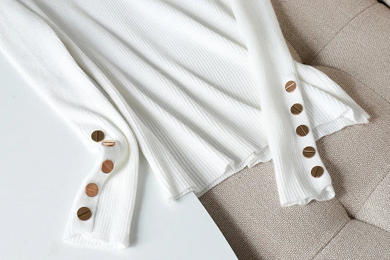 White ribbed sweater with brown buttons on a beige surface