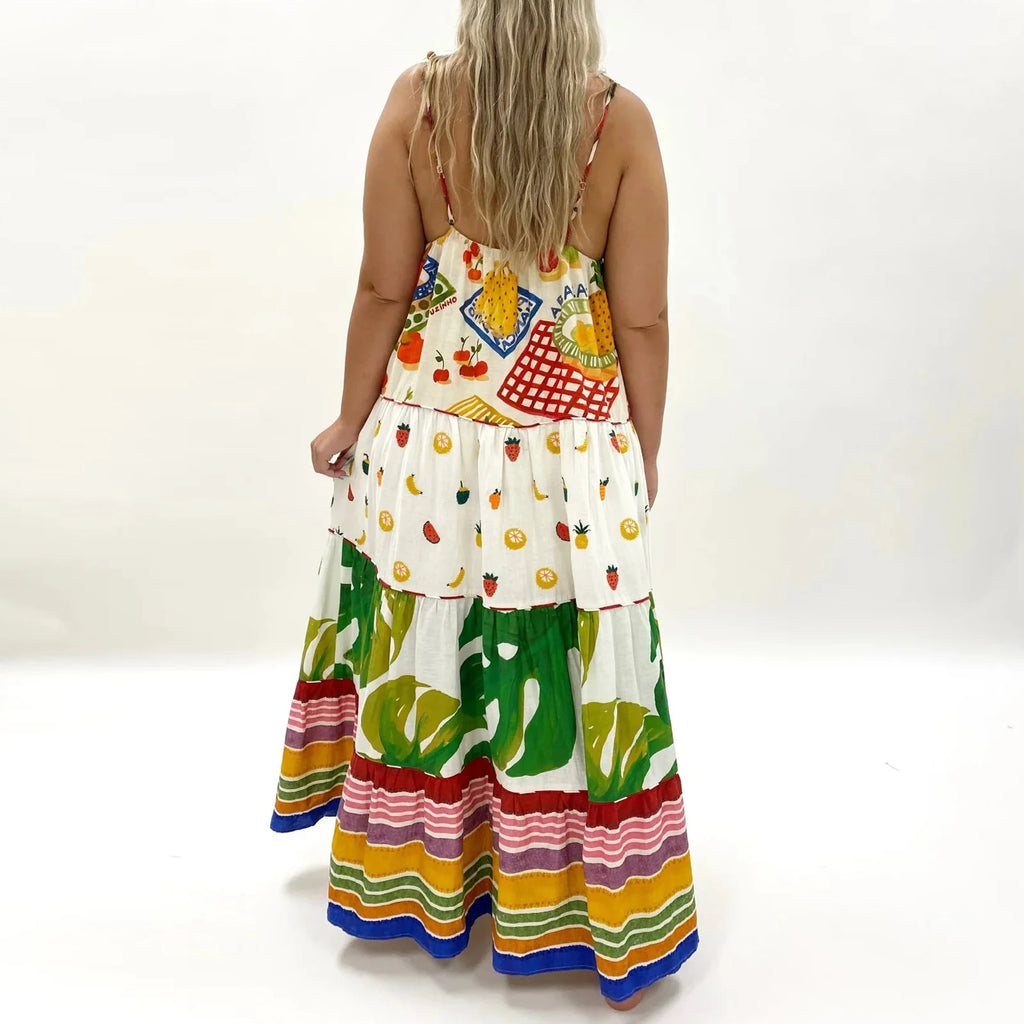 Woman wearing a colorful dress with fruit patterns on a white background