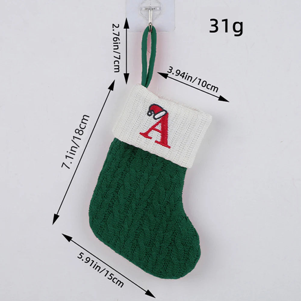 Green knitted Christmas stocking with white cuff featuring a red letter 'A', showing measurements and weight on a light gray background.