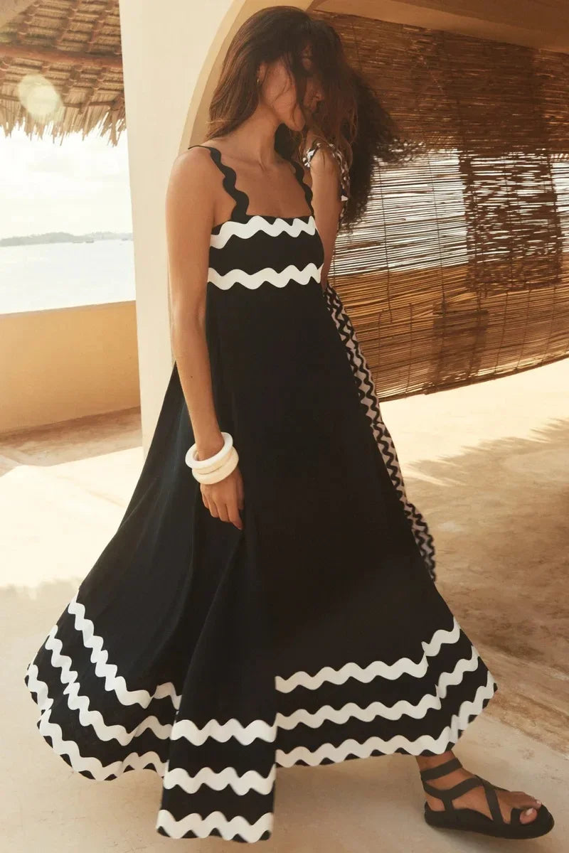 Woman wearing a black and white dress with wavy patterns in a tropical setting.
