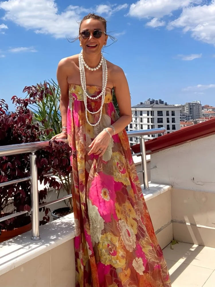 Woman in a colorful floral dress standing on a balcony with buildings in the background