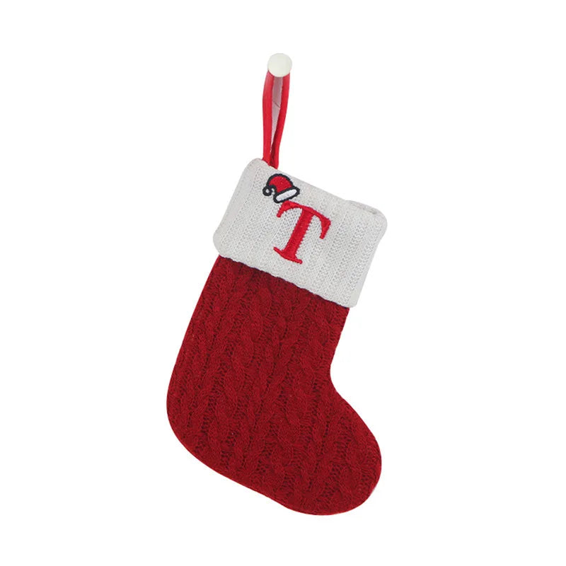 Red and white knitted Christmas stocking with a letter 'T' on a white background