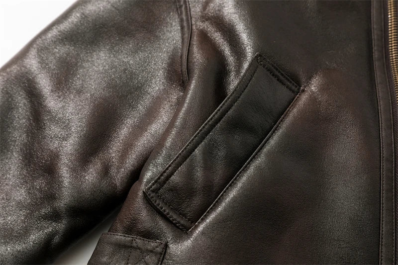 Close-up of a brown leather jacket with a pocket detail on a white background