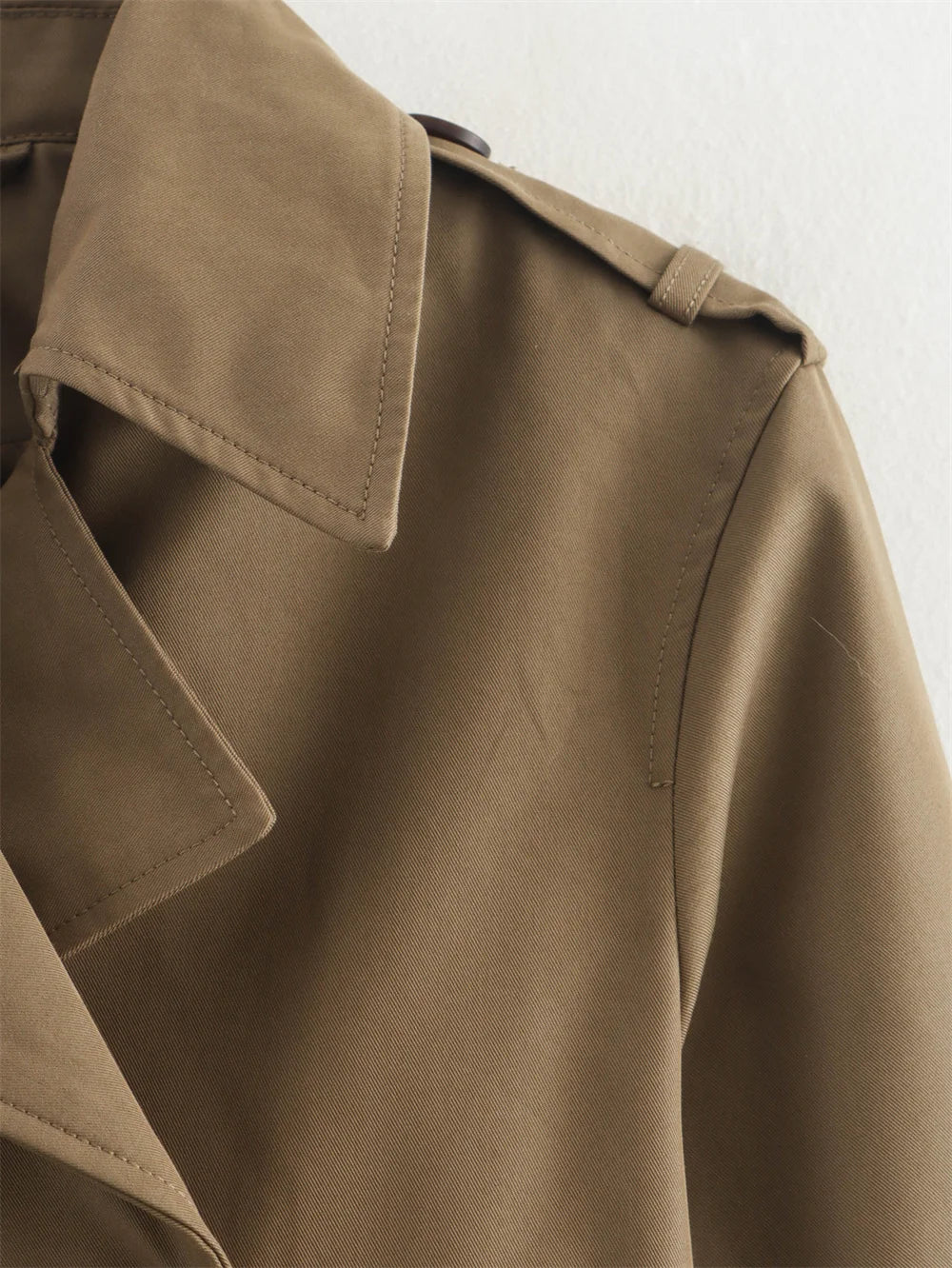 Close-up of a brown trench coat on a light background