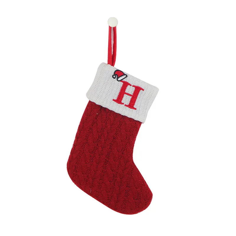 Red knitted Christmas stocking with white cuff featuring a letter 'H' on a white background