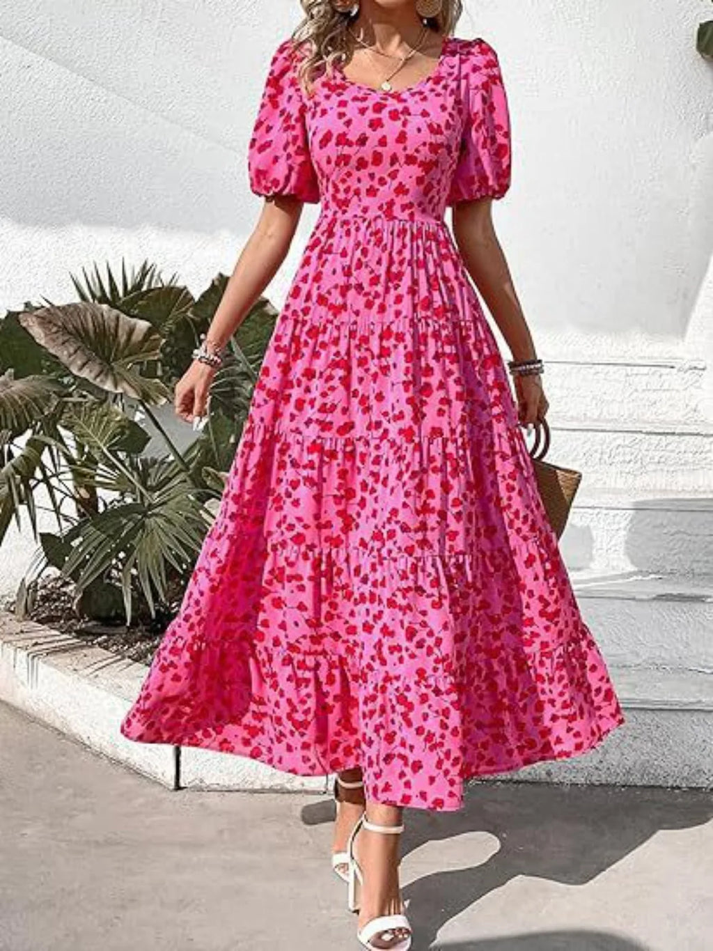 Woman wearing a pink floral dress with puff sleeves in an outdoor setting.