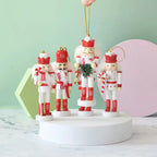 Set of four nutcracker ornaments on a white platform with a light green background