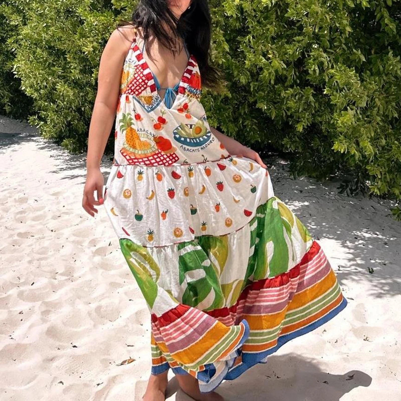 Woman wearing a colorful dress with fruit patterns on a sandy background